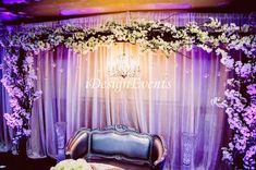 a couch sitting in front of a purple and white backdrop with flowers on the back