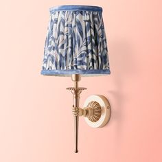 a blue and white lamp on a pink wall next to a light fixture that is attached to the wall