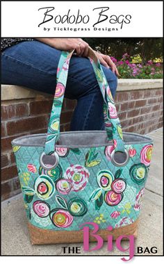 a woman is sitting on a brick wall holding a large handbag with floral designs