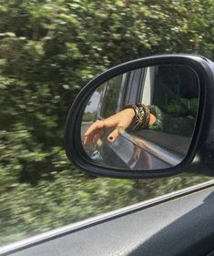 a woman's reflection in the side view mirror of a car as she drives