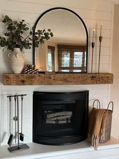 a fireplace with a mirror above it next to a potted plant and other items