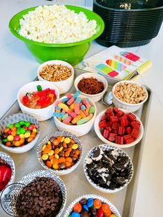 a table topped with bowls filled with different types of candy and candies next to a bowl of popcorn