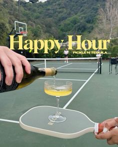 a person pouring wine into a glass on top of a tennis court