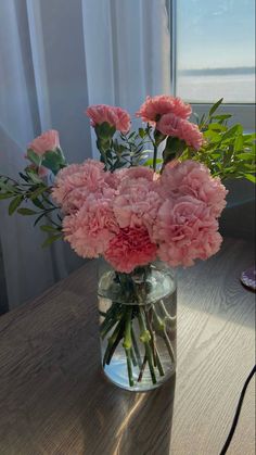 pink carnations in a glass vase on a table