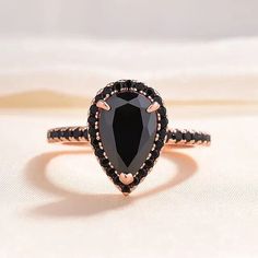 a black diamond ring on top of a white surface with gold trimmings and accents