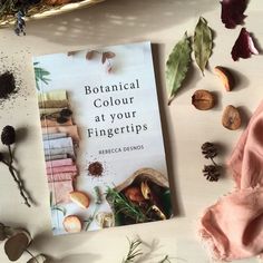 the book botanical color at your fingertipstips sits on a table next to dried herbs and leaves