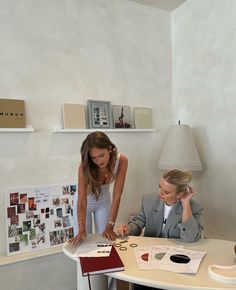 two women sitting at a table working on something