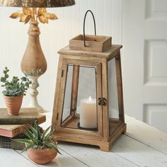 a small wooden lantern sitting on top of a table next to books and a plant