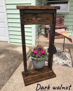 a potted plant sitting on top of a wooden stand in front of a house