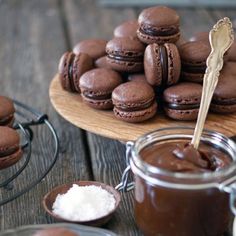 chocolate macaroons are sitting on a plate next to a jar of powdered sugar