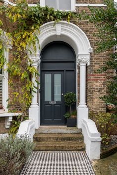 a black and white checkered floor in front of a house with an arched door