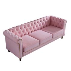 a pink velvet couch with gold trimmings on the arms and back, sitting in front of a white background