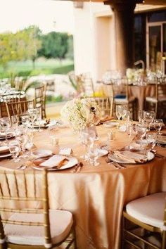 the table is set with gold linens and place settings for guests to sit at