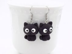 a pair of black cat earrings on a white cup