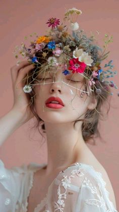 a woman with flowers in her hair wearing a white dress and holding her hands to her head