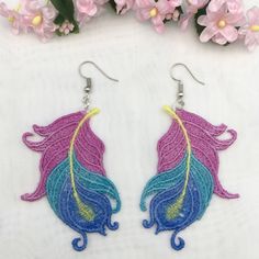 two pairs of earrings with colorful feathers on them