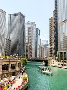 a boat traveling down a river in the middle of a city filled with tall buildings