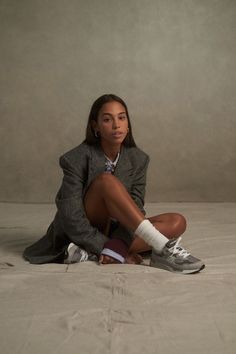 a woman sitting on top of a bed wearing sneakers