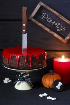 a red cake sitting on top of a table with a knife stuck in the frosting