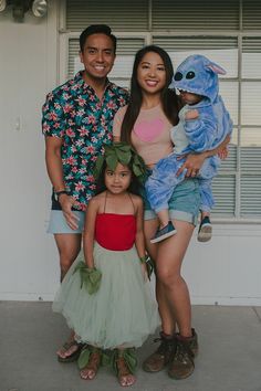 a man, woman and child posing for a photo with monsters on their heads in front of a building