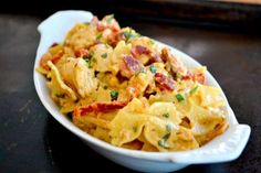 a white bowl filled with pasta covered in cheese and bacon sauce on top of a wooden table