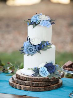 a white and blue wedding cake with flowers on the top is sitting on a table