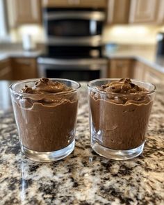 two glasses filled with chocolate pudding on top of a counter