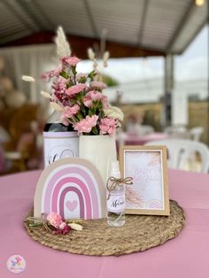 a table with pink flowers and baby's breath bottles on it, next to a photo frame