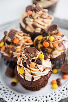 chocolate cupcakes with white frosting, candy and candies on a plate