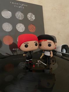 two figurines sitting on top of a record player