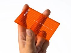 a hand holding an orange business card with dots on the front and back side, against a white background