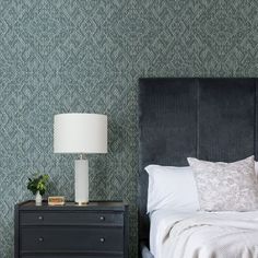 a bedroom with green wallpaper and a black headboard next to a night stand