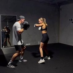 a man standing next to a woman with boxing gloves on and punching her face in the mirror