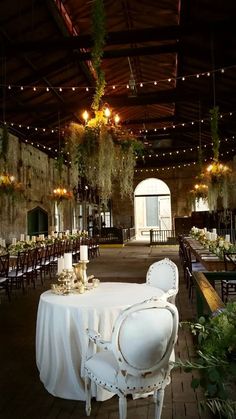 an indoor dining area with tables and chairs covered in white cloths, hanging from the ceiling