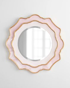 a pink and gold mirror on the wall