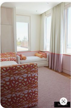 a living room filled with furniture next to two large windows covered in pink and orange curtains