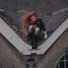 a woman with red hair sitting on top of a roof