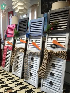 several wooden shutters decorated with ribbons and bows are lined up on the floor in front of a window