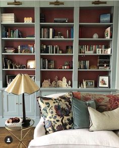 a living room filled with lots of bookshelves next to a couch and lamp