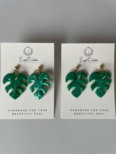 two pairs of earrings with green leaves on the front and back of each earring