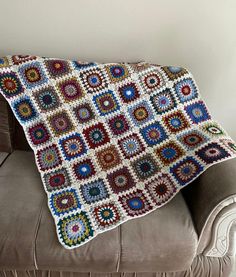 a crocheted granny's afghan sits on a couch with the blanket draped over it