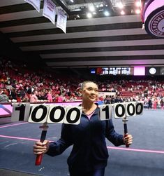 a woman holding two tennis racquets in front of her face with the number 100 on it