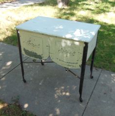 an old desk is sitting on the sidewalk in front of a tree and grass area