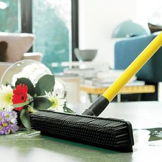 a cleaning brush sitting on top of a table next to flowers