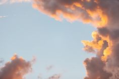 an airplane is flying in the sky with some clouds behind it at sunset or dawn