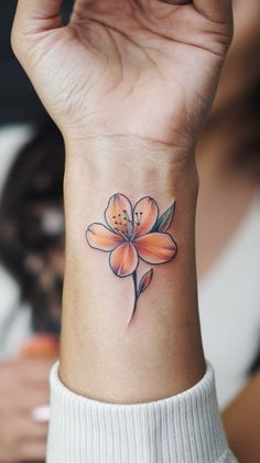 a woman's wrist with a flower tattoo on the left side of her arm