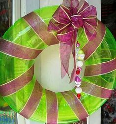 a green wreath with pink ribbon and beaded beads hanging on the front door window