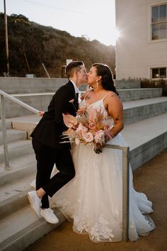 a bride and groom kissing on the steps