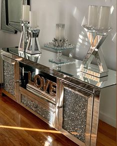 a mirrored console table with love written on the front and bottom, surrounded by two crystal candlesticks