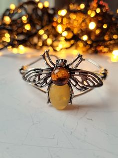 ❤ This handmade amber bee bracelet is an exquisite piece of jewelry that beautifully combines the elegance of amber with the charming motif of a bee.  ❤ Each cuff bracelet contains polished cognac, green & butterscotch Baltic amber stones with natural fossils inside, so every bracelet is unique & one of a kind. ❤ In folklore, bees are associated with the harmony of the nation and family, close friendship, and spiritual life. So, a jewelry with a cute bee motif can be a warm & cosy gift for a fri Bee Charm For Bracelet, Bee Bracelet, Amber Bracelet, Amber Stone, Queen Bee, Spiritual Life, Bracelet Bangle, Nature Bracelets, Queen Bees